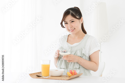 ヨーグルトを持つ笑顔の女性と朝食