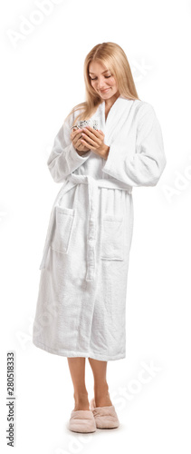 Beautiful young woman in bathrobe drinking coffee on white background