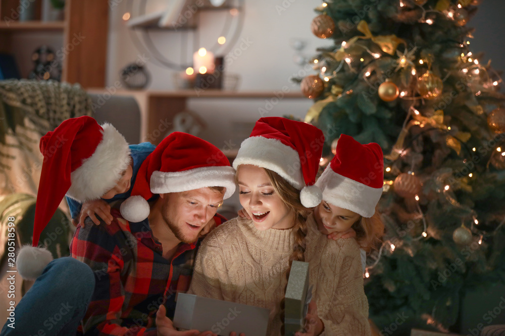 Happy family opening Christmas gifts in evening Happy family opening Christmas gifts in evening