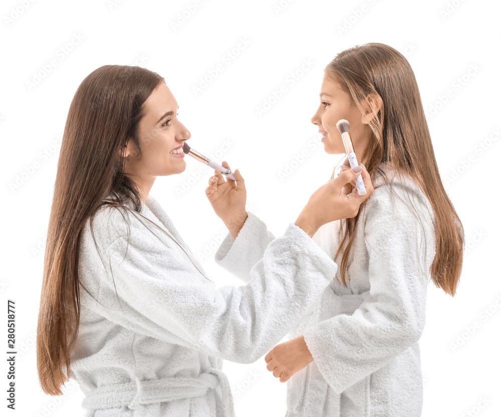 Mother and her little daughter in bathrobes applying makeup against white background Mother and her little daughter in bathrobes applying makeup against white background
