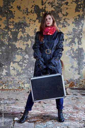 Girl in a black cloak with a diplomat in a ruined room. A spy in a secret meeting. Unusual photo shoot photo