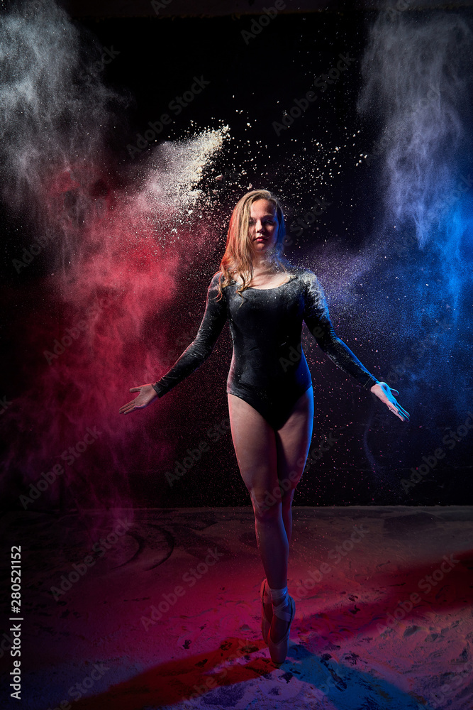 Young teen girl in a dark room during a photoshoot with flour with a colored light and a black background