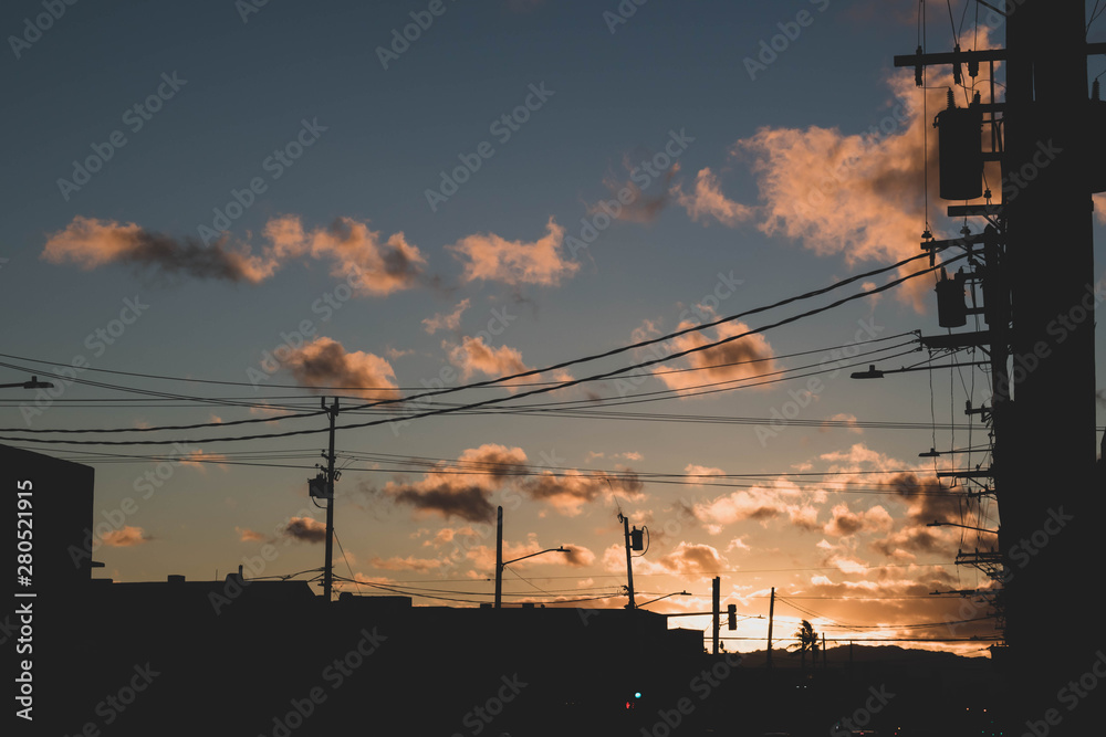 Sunset over the city with powerlines and buildings silhouted in the foreground and peach and powder blue color in the foreground. Shot in the Makiki area in Honolulu, Oahu,Hawaii. Plenty of copy space