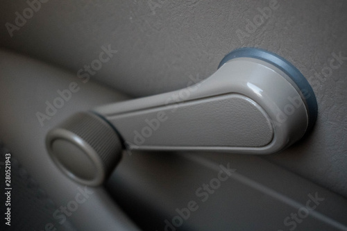 Hand crank, non-electric, manual car window in a dove grey color an old vehicle.