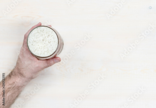 Male hand holding beer light wooden background. Top view. Empty space for text