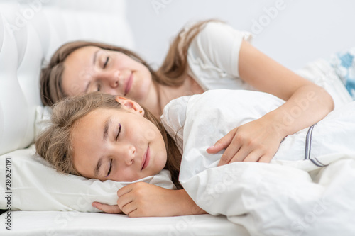 Mother and daughter sleep together on the bed at home