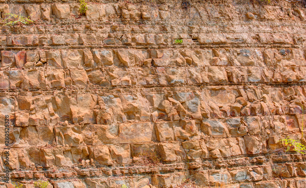 Cracked natural red rock wall - The texture of the wall of crushed natural stone is light red Cracked natural red rock wall - The texture of the wall of crushed natural stone is light red