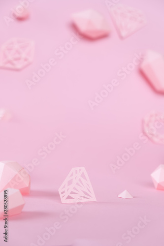 A variety of faceted gemstones, made of paper on a pink background.