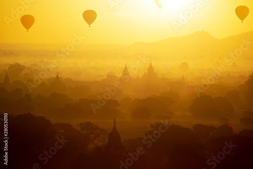 Ancient temple and hot air balloon fly over sky in Bagan after sunrise