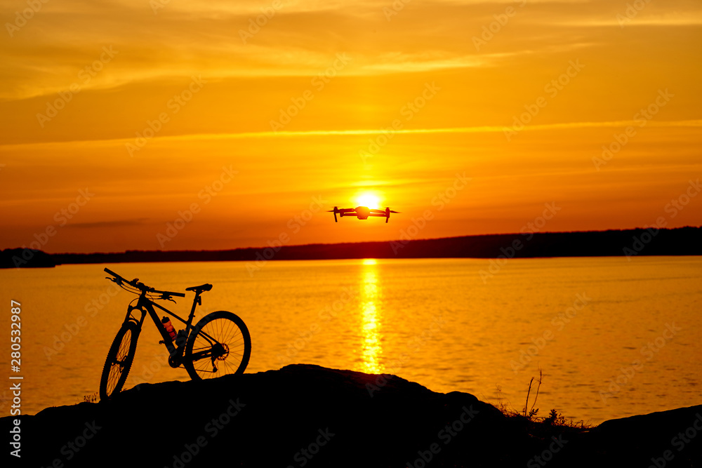 Fototapeta premium silhouette of a bicycle at sunset. drone quadcopter with digital camera flying at sunset