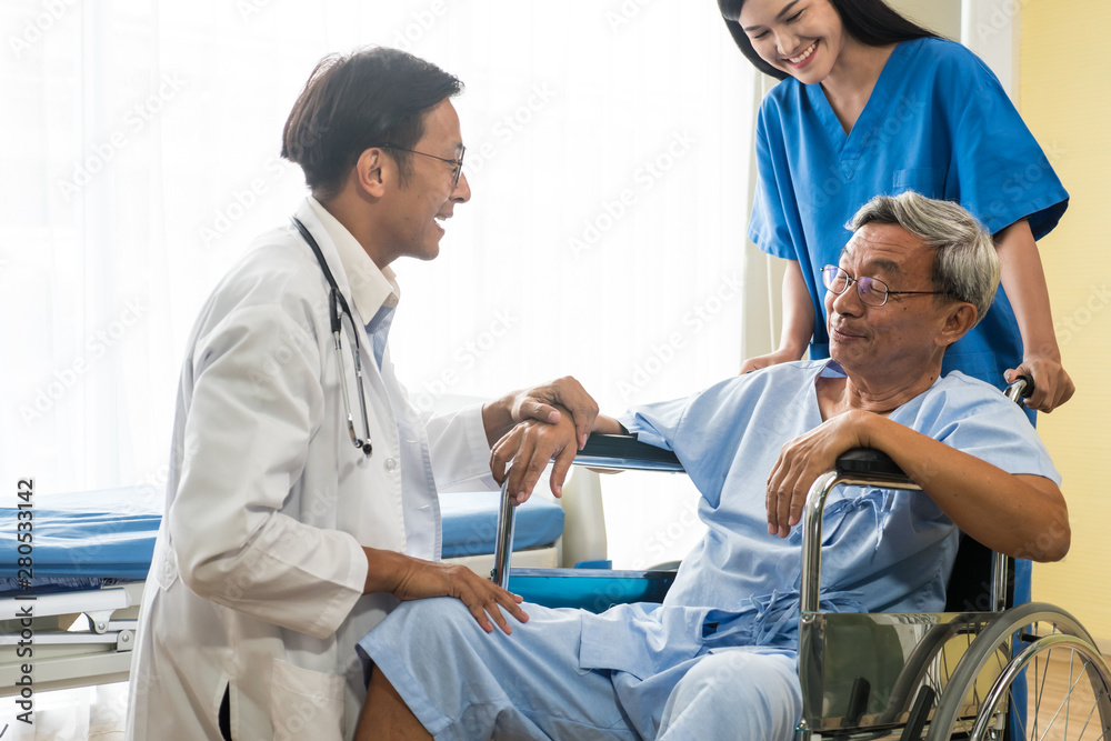 Doctor and physiotherapist talking to elderly patient sitting on wheelchair. Doctor and physiotherapist talking to elderly patient sitting on wheelchair.
