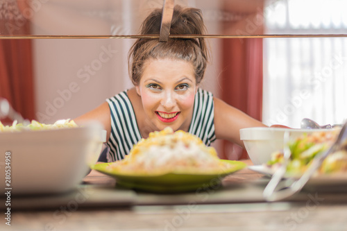 Portrait of a beautiful smiling woman posing with saucers in the buffet