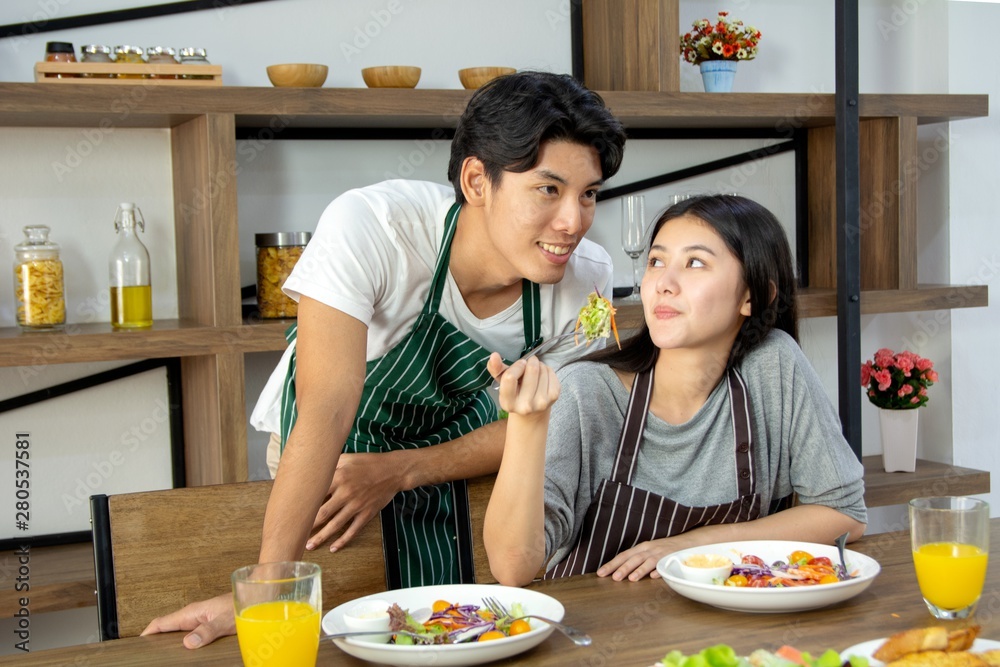 Cute happy couple having breakfast having salad in modern kitchen and having a good time