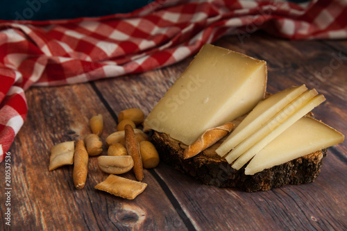 piece and slices of typical Spanish cheese on wood