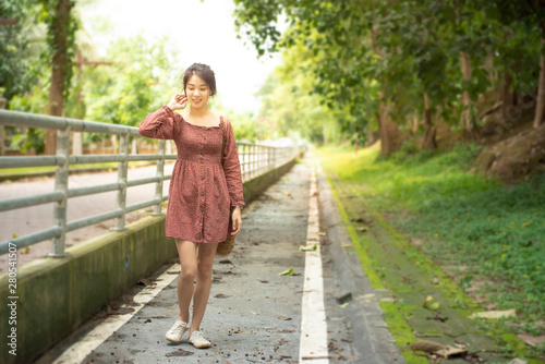 Asian woman in casual dress walk with smile on footpath in outdoor park and copy space with blur of background,vintage style