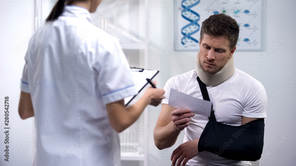 Patient in foam cervical collar and arm sling reading doctors prescription Patient in foam cervical collar and arm sling reading doctors prescription
