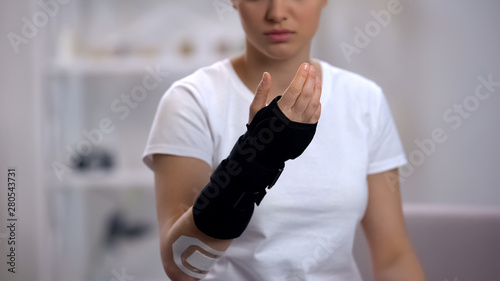 Female checking titan wrist brace, rehabilitation after sports trauma, treatment