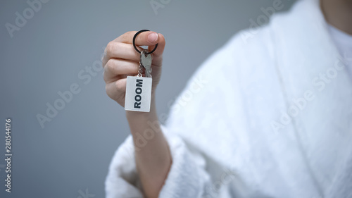 Person in bathrobe holding keys with Room word, health resort sanatorium, spa
