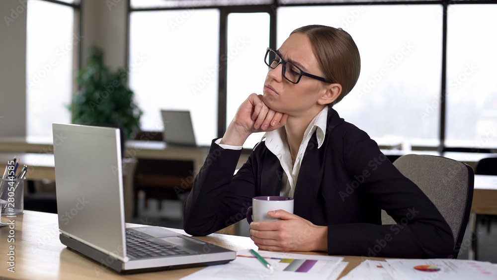 Bored woman having coffee break in office, dissatisfied with work, lack of ideas Bored woman having coffee break in office, dissatisfied with work, lack of ideas