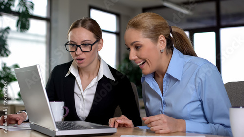 Female managers reading great news on laptop, rejoicing successful startup