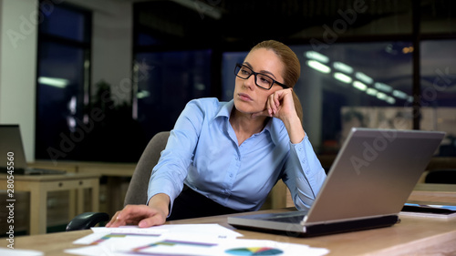 Woman sitting upset hating job while working night shift in office, overtime