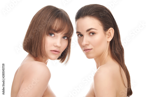 Beauty portrait of two beautiful young girls with beautiful glowing skin and natural skin on white background