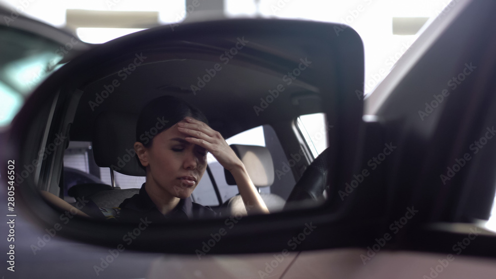 Upset patrolwoman suffering migraine, sitting in police car, busy lifestyle