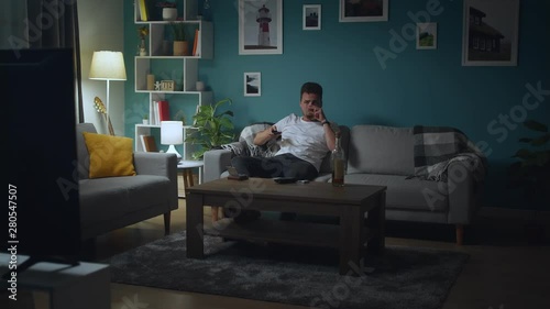 drunk middle-aged man feeling depressed watching tv on his couch at home