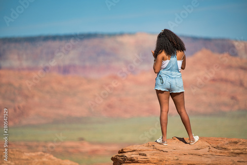 African girl standing on the top of a rock enjoying the canyon, back view