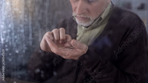 Canvas Print Unhappy male pensioner counting coins hand, old age poverty, social instability