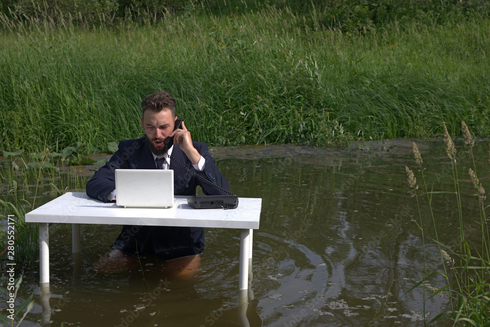 Office routine. bearded man with a surprised face talking on the phone at the office desk. Sitting in the swamp Office routine. bearded man with a surprised face talking on the phone at the office desk. Sitting in the swamp