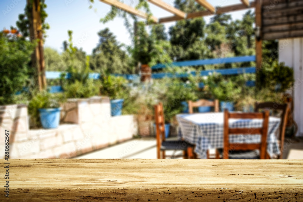 Fototapeta premium Table background and spring time. Green garden outside the winfow in blurred view. Empty space for decoration and an advertising product.