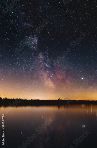 Night view of the colorful milky way with many stars over the horizon in the german mountains with lake reflections. Harz National Park R