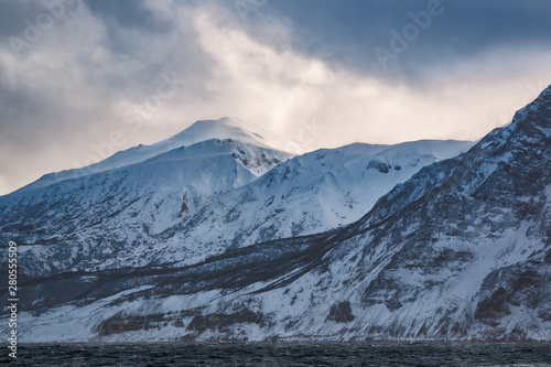 rocky coast of one of the Kuril Islands in the winter during a snow storm