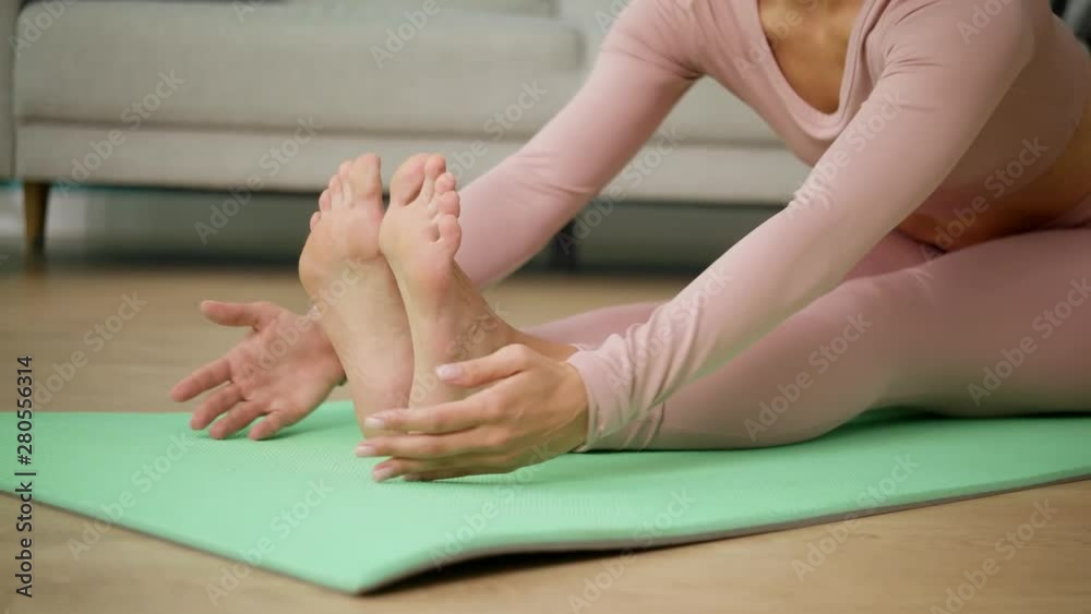 Young beautiful athletic woman in pink sportswear doing yoga and stretching