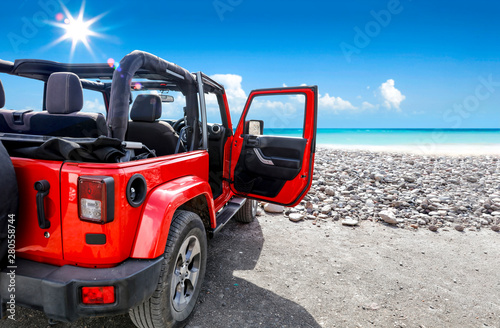 A red jeep on sandy beach and beuatiful blue sunny sky view in summer time. photo