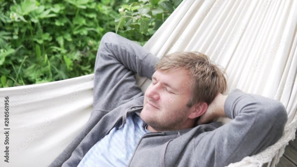 Relaxed man lying in a hammock in the summer on the veranda. Relaxed man lying in a hammock in the summer on the veranda.