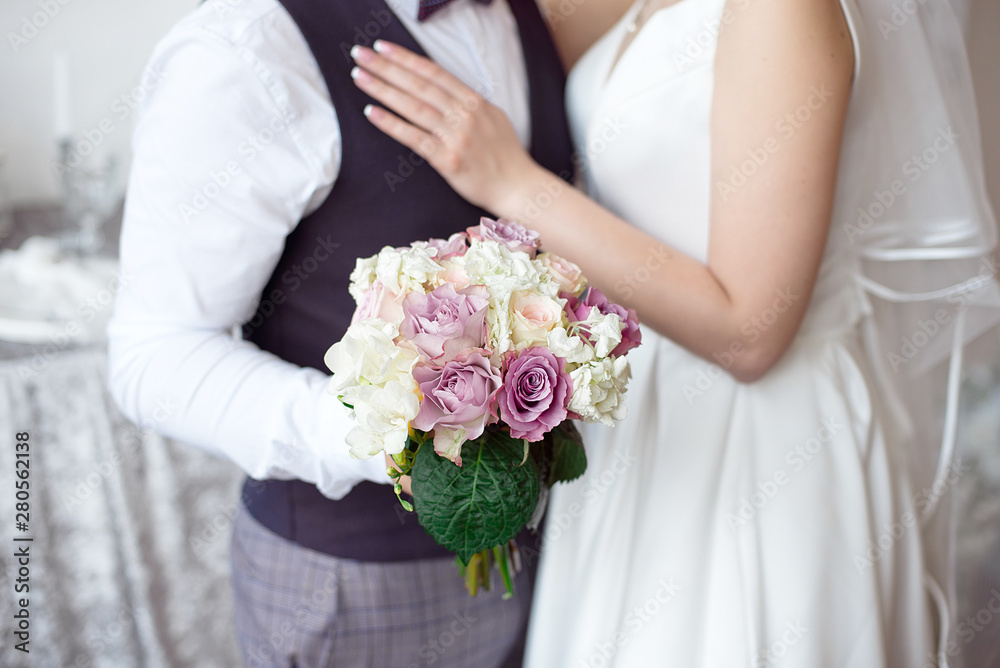 Hands of the bride and groom with wedding rings and a bouquet of flowers. Hands of the bride and groom with wedding rings and a bouquet of flowers.