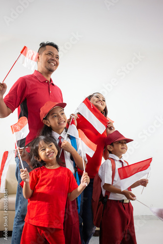 proud indonesian family holding indonesia flag over white background on independence day