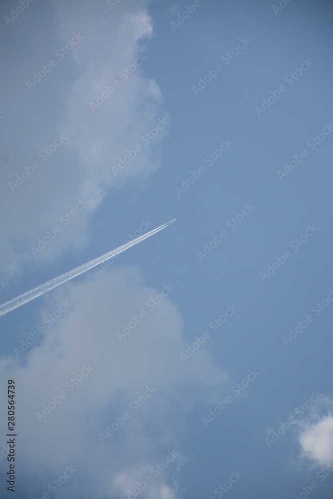 The plane soars up against the blue sky with clouds The plane soars up against the blue sky with clouds