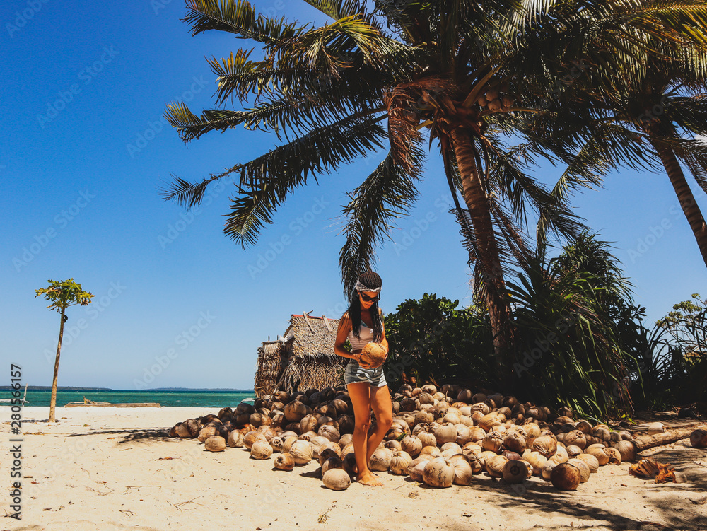 Woman holding coconut shells in the palm tree jungle in Onok island in ...