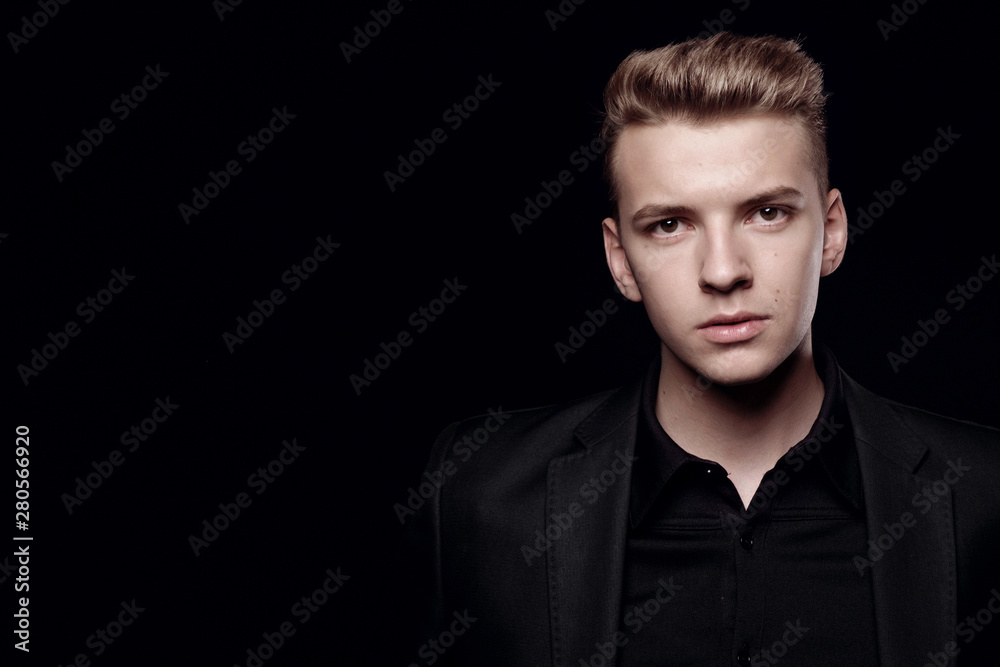 young man in black jacket on black background