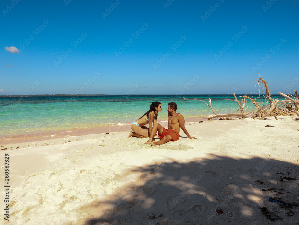 Lovely couple relaxing at the white sandy beach with palm trees in Onok Island in Balabac Palawan in Philippines