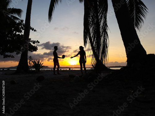 Lovely couple watching sunset with palm trees in Candaraman Island in Balabac Philippines photo