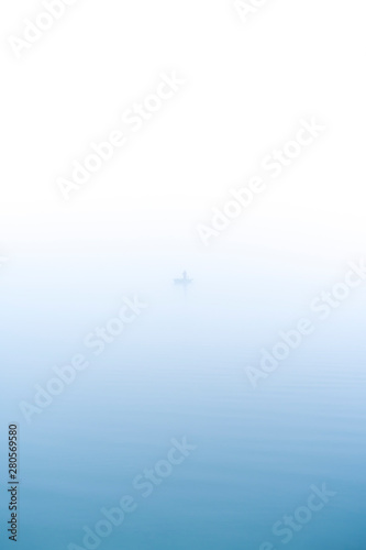 Angler in morning mist standing in a boat