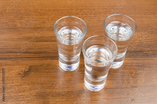 Three glasses of vodka on a wooden table