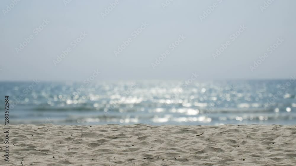 4K. sand with blurred ocean water wave tropical beach bokeh background with sound of the sea, summer vacation and travel concept with copy space