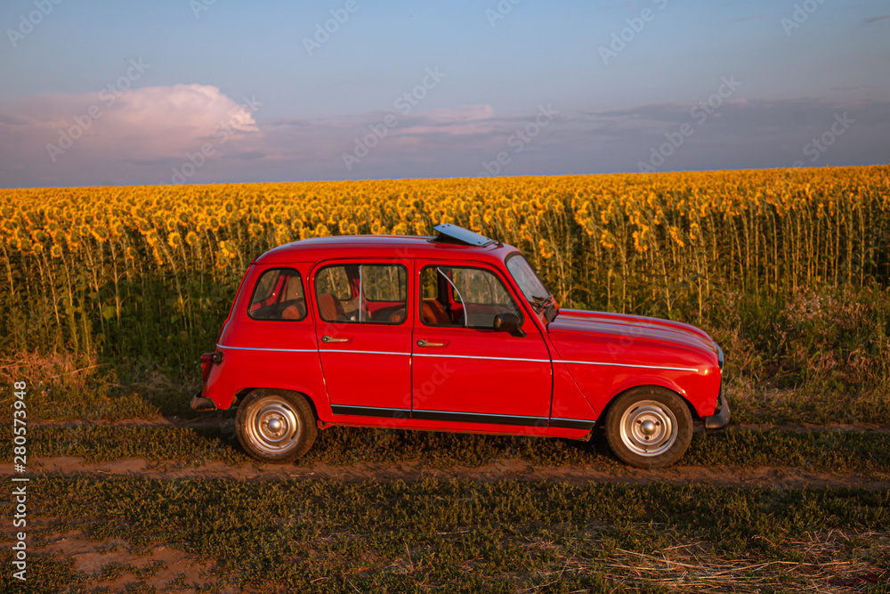 Fototapeta premium red retro car on a field in the setting sun