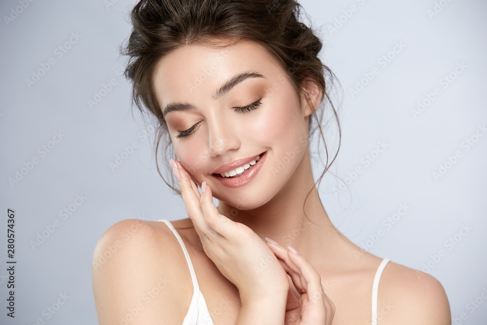 woman with perfect nude make-up with golden shadow smiling and touching face