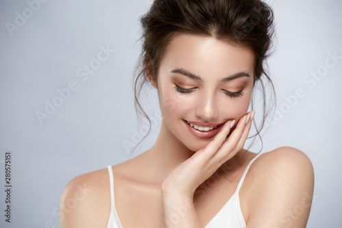 beautifuk girl with golden make-up and in white t-shirt touching cheek and smiling
